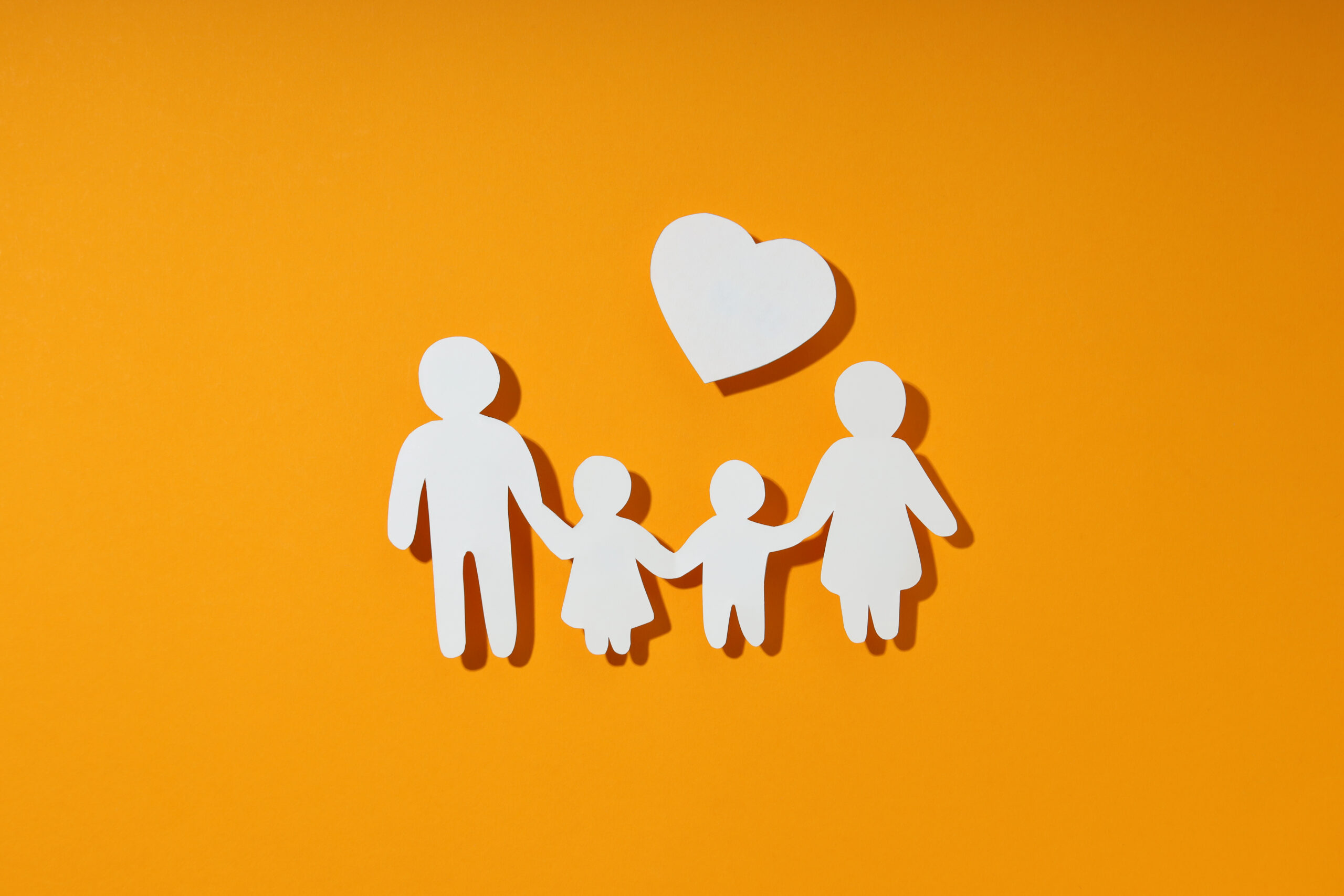 Weißer Scherenschnitt einer Familie vor orangem Hintergrund